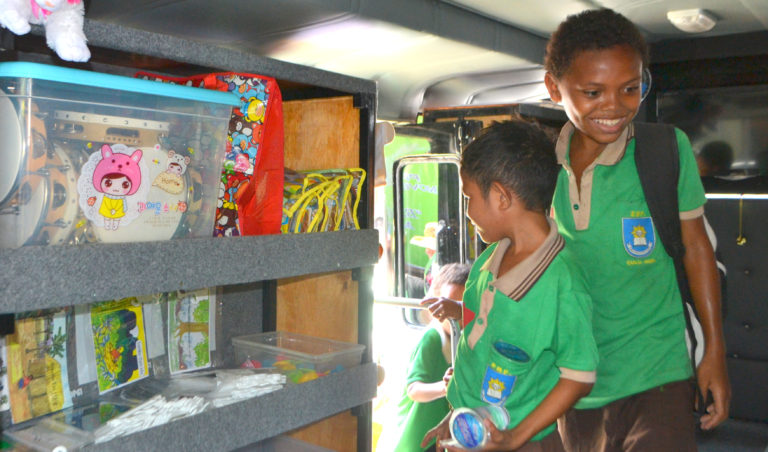 Two Timorese boys looking at toys on mobile literacy bus