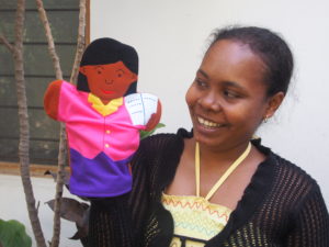 A school teacher holding a puppet in her hand used to teach health literacy