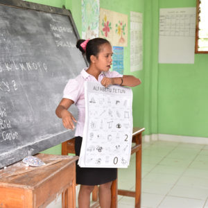 Timorese Teacher standing at front of class with poster