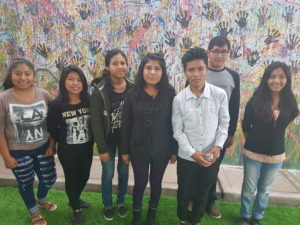 Group of students from Peru standing in front of painted mural at school