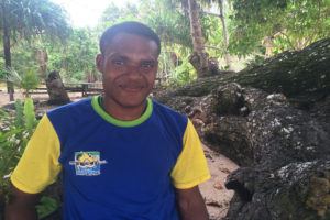 Young man from Papua New Guinea standing outside in forest looking directly at the camera