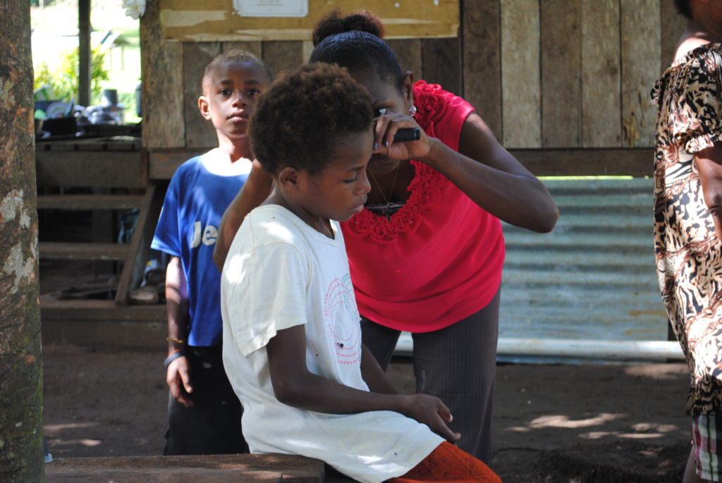 Young boy having his ears examined by a women outside in a village in Papua New Guinea