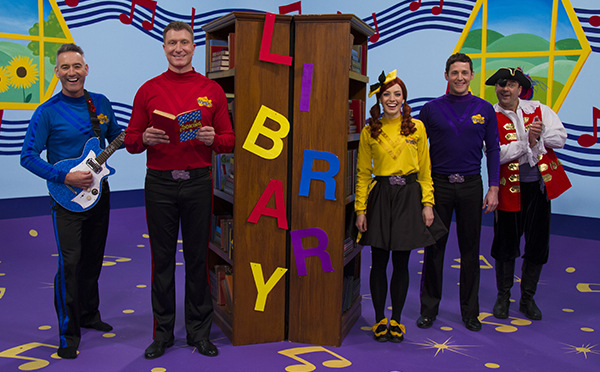 A photo of The Wiggles in a Library holding books