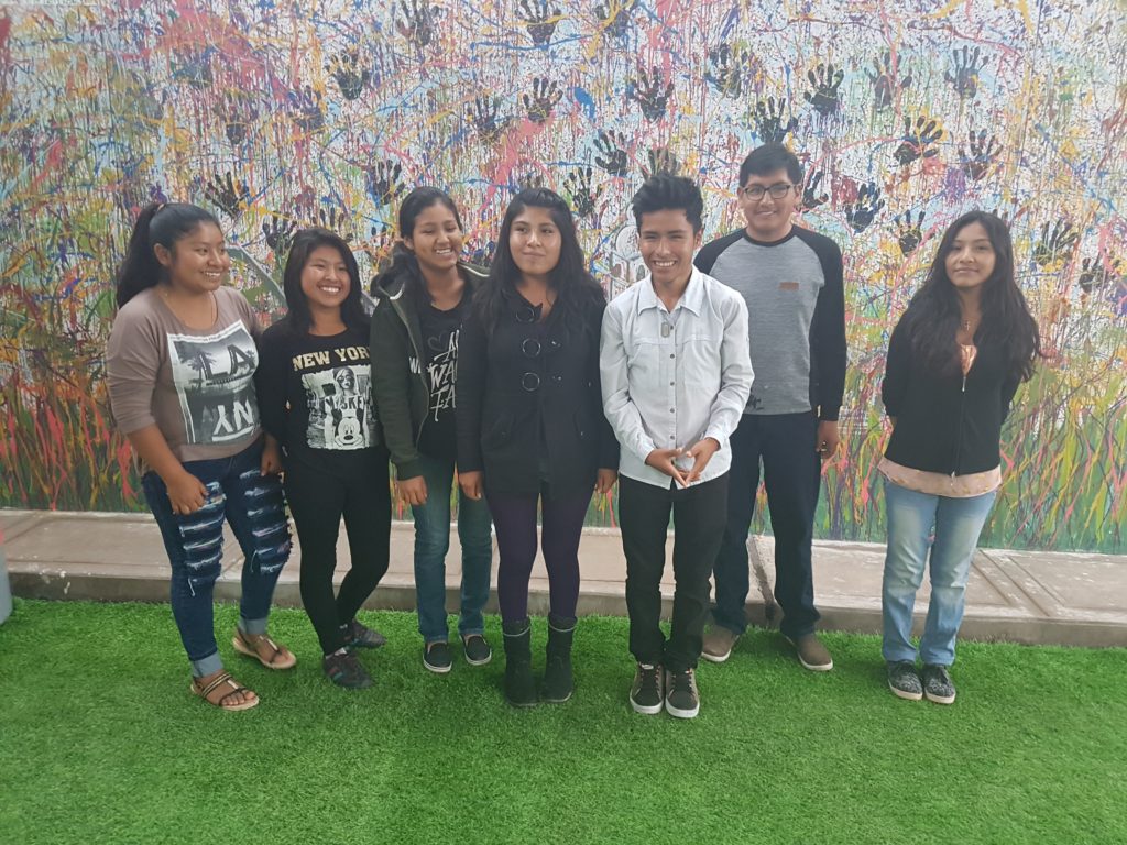 Students in Peru standing in front of a mural made up of different coloured handprints