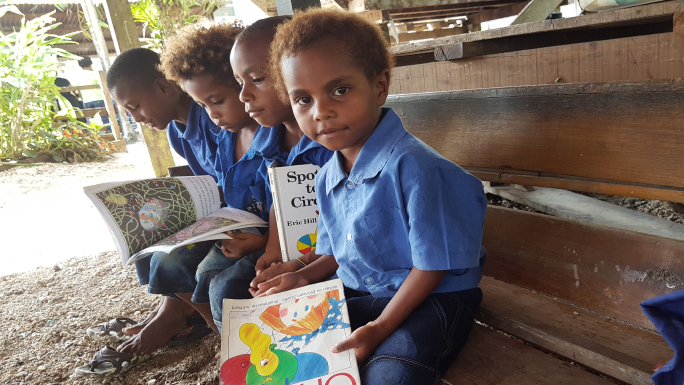 Four boys from PNG looking at books
