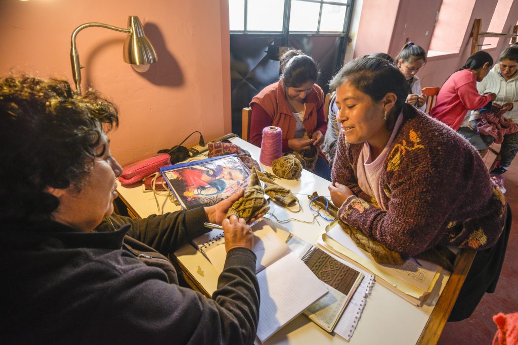 Two Peruvian women knitting in a workshop
