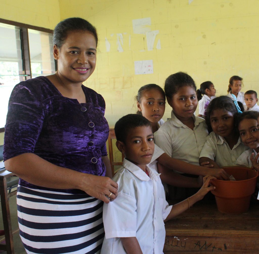 Teacher standing with students in classroom in Timor-Leste