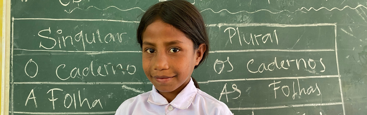 Student in Timor-Leste standing in front of blackboard
